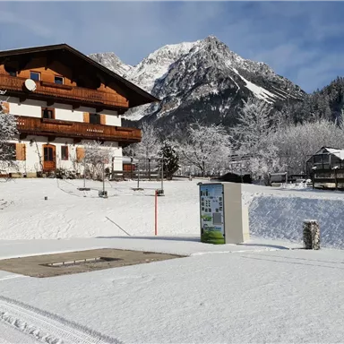 Ein schönes Holzhaus in einer verschneiten Landschaft. Die Bergkulisse im Hintergrund ist beeindruckend.