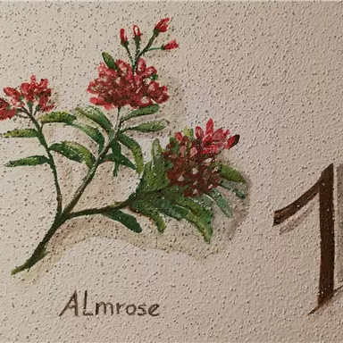 Eine Wandmalerei mit roten Blumen und grünen Blättern. Neben den Blumen steht die Zahl eins und der Schriftzug „Almrose“.