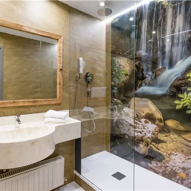 A modern bathroom with a marble sink and a large shower. In the background, there is a mural of a waterfall and green plants.