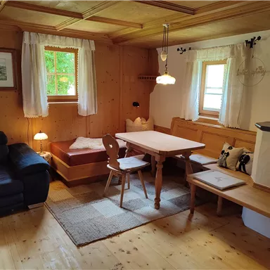 A cozy living room with wooden paneling and a dining area. The windows let in plenty of natural light and create an inviting atmosphere.
