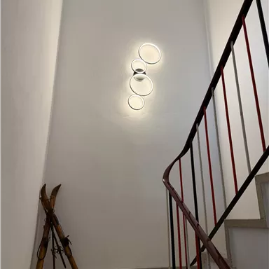 A bright staircase with modern wall lights. In the corner stands a pair of skis.