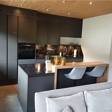 Modern, elegant kitchen with dark furniture and a central wood island. The rooms are designed to be bright and inviting.