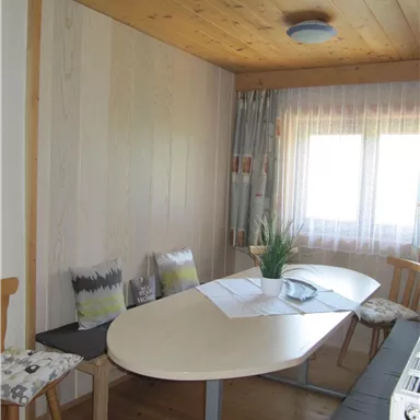 A bright room with an oval table and chairs. Large windows let in plenty of daylight.