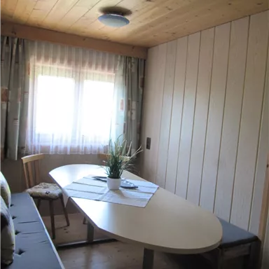 A cozy room with an oval table and chairs. The window lets in a lot of daylight.