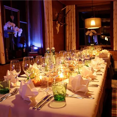 A festively set table in a cozy room. The table decoration includes glasses, napkins, and candles for an inviting atmosphere.