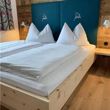 Ein gemütliches Schlafzimmer mit einem Doppelbett und weißen Kissen. Die Wände sind aus Holz, und es gibt sanfte Beleuchtung.
