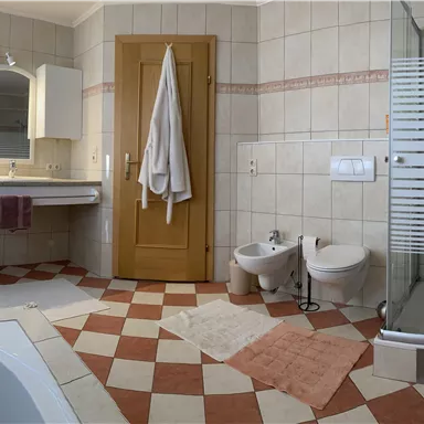 A modern bathroom with a quartz floor covering and a shower. The walls are tiled in light colors, and there are two sinks as well as a bathtub.