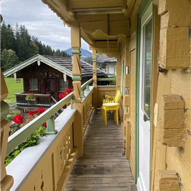Ein Holz-Balkon mit Sitzgelegenheit bietet schöne Ausblicke auf die umliegenden Wiesen, den Bauerngarten und das alte "Waschhaus"