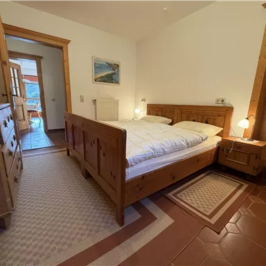 Ein gemütliches Schlafzimmer mit einem Holzbett und Nachttischen. Der Raum hat einen warmen, einladenden Eindruck und ist gut beleuchtet.