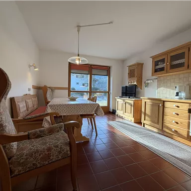 Eine gemütliche Ferienwohnung mit Holzdetails und viel natürlichem Licht. Der Wohnbereich umfasst einen Essplatz und eine kleine Küche.