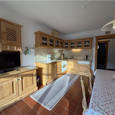 Eine gemütliche Küche mit Holzschränken und moderner Ausstattung. Der Tisch ist für eine Mahlzeit gedeckt und der Raum ist hell und einladend.
