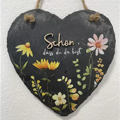 A heart-shaped slate sign with colorful floral motifs. It features the inscription "Nice to have you here".
