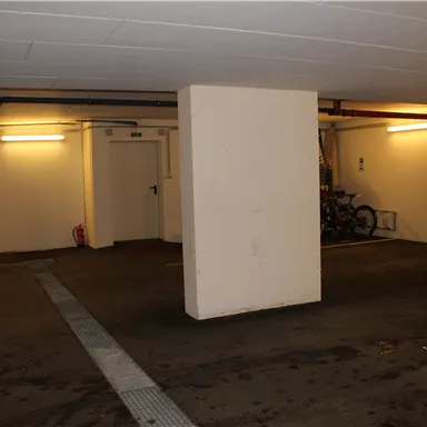 Ein leerer Parkplatz mit einem Säule in der Mitte. Die Wände sind hell und die Beleuchtung ist weich.