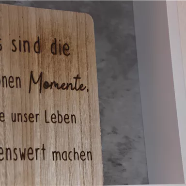 A wooden sign with the inscription: "It is the beautiful moments that make our life worth living." The background is neutral and light.