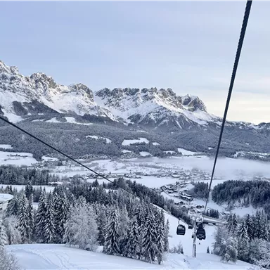 A picturesque winter landscape with snow-covered mountains and fir trees. Cable cars take visitors to the ski resorts.