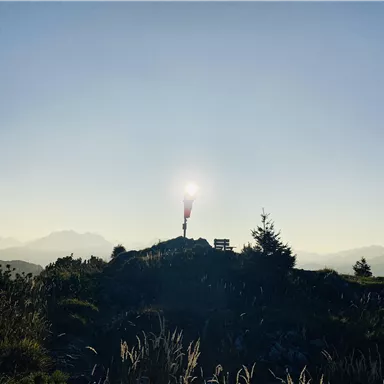 Eine herrliche Berglandschaft im Sonnenlicht mit einem roten Windsack. Im Hintergrund sind einige Berge und ein klarer Himmel zu sehen.