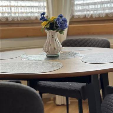 A round table with an elegant bouquet in a vase. The atmosphere is cozy and inviting.
