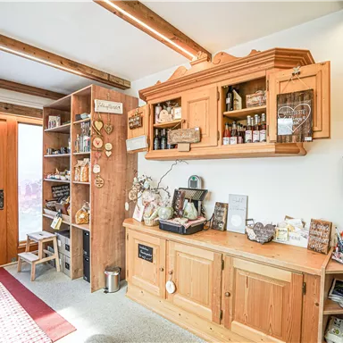 Ein gemütlicher Raum mit Holzregalen und einer dekorativen Fensterfront. Der Tisch ist mit verschiedenen Leckereien und Souvenirs gefüllt.