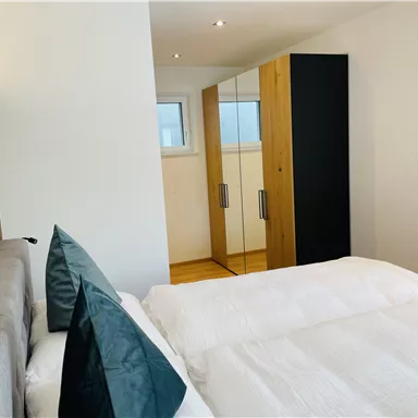 A modern bedroom with a large bed and an elegant wardrobe. The rooms are designed to be bright and friendly.