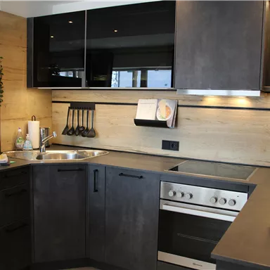 A modern kitchen with dark furniture and a light countertop. It features modern appliances and is well organized.