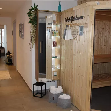 A bright hallway with a wooden sauna area. On the left side, there are cozy seats and decorative elements.