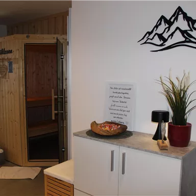 A cozy wellness area with a wooden sauna and modern decor. Plants and decorative elements give the room a relaxing atmosphere.