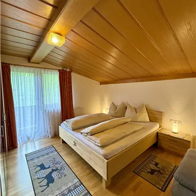 A cozy bedroom with a large bed and wooden floor.  
Large windows let in plenty of light and create an inviting atmosphere.