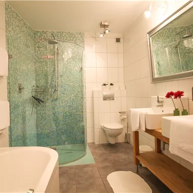 Ein modernes Badezimmer mit einer transparenten Duschkabine und einem schönen Badewanne. Die Wände sind mit hellen Fliesen und einer blauen Musterung gestaltet.