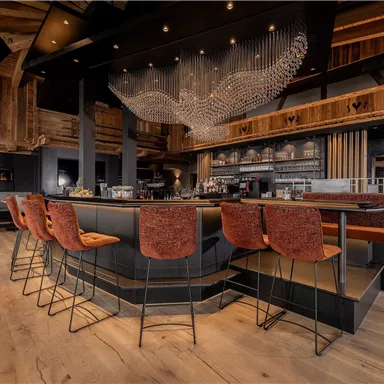 A modern bar with stylish chairs and an elegant wooden ceiling. The ambiance is cozy and inviting.