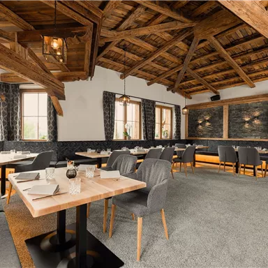 An elegant restaurant with a wooden beam ceiling and modern furniture. The atmosphere is welcoming and cozy.