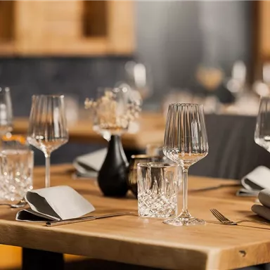 An elegant table in a restaurant with glasses and cutlery. The table decoration consists of a small vase and stylish napkins.