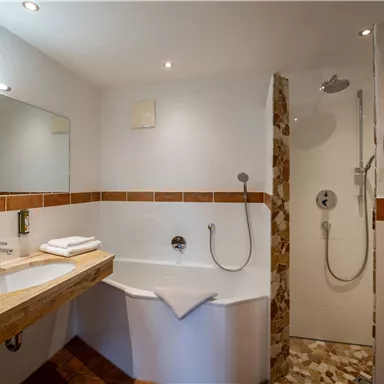 A modern bathroom with a bathtub and a shower. The walls are bright and the decor is simple and elegant.