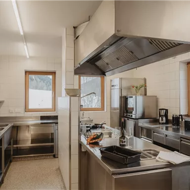 A modern kitchen with stainless steel appliances and large windows. The space is bright and well-organized.
