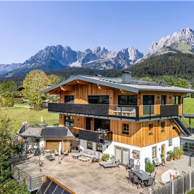 Ein modernes Holzhaus umgeben von einer schönen Landschaft und majestätischen Bergen. Die Terrasse bietet einen herrlichen Blick auf die Natur.