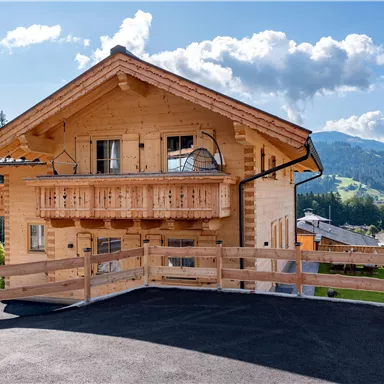 Ein traditionelles Chalet aus Holz in einer malerischen Berglandschaft. Die Umgebung ist grün mit schönen Bergen im Hintergrund.