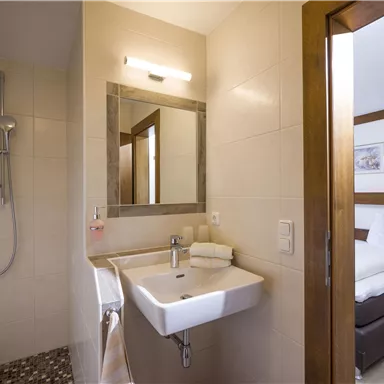 A modern bathroom with a shower, sink, and mirror. The space is bright and friendly designed.