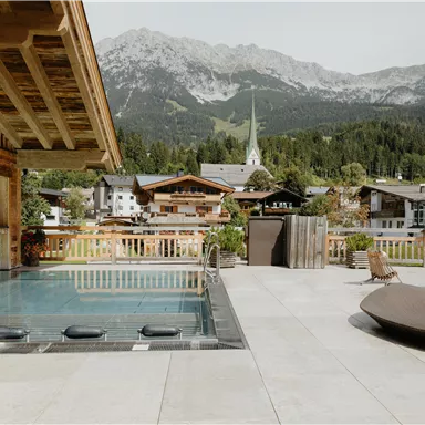Ein schöner Poolbereich mit Blick auf die Berge. Die Umgebung ist ruhig und eingebettet in eine malerische Alpenszenerie.