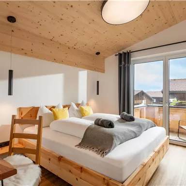 Ein modernes Schlafzimmer mit Holzwänden und einem großen Fenster. Es gibt ein gemütliches Bett und einen Holzstuhl, der für eine entspannende Atmosphäre sorgt.