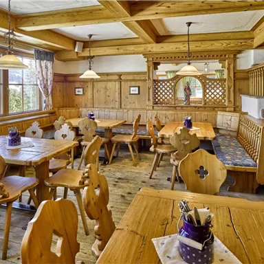A cozy restaurant with wooden furniture and rustic decor. The large windows provide plenty of daylight in the inviting space.