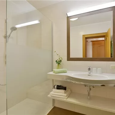 Ein modernes Badezimmer mit Dusche und Waschbecken. Der Raum ist hell und freundlich gestaltet.