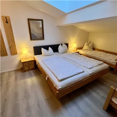 Ein gemütliches Schlafzimmer mit zwei Betten und sanftem Licht. Die Holzdecke und -möbel verleihen eine warme Atmosphäre.