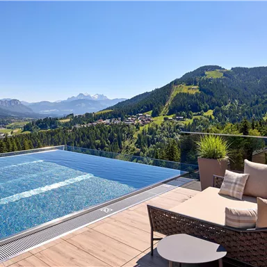 A luxurious pool with a view of the mountains and the surrounding landscape. A cozy seating area invites you to relax.