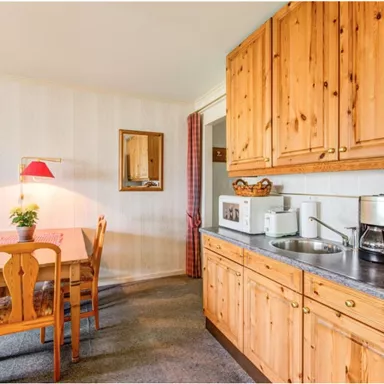 Eine gemütliche Küche mit Holzschränken und einem Esstisch. Die Zimmer haben eine warme, freundliche Atmosphäre.