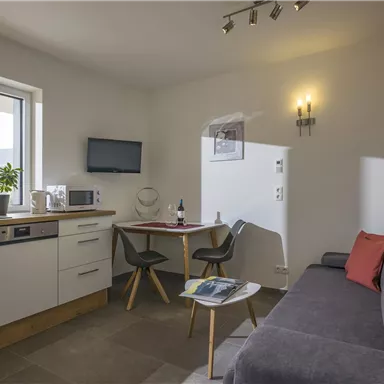 Eine moderne und helle Wohnung mit einer kleinen Küche und einem gemütlichen Wohnbereich. Der Raum ist freundlich eingerichtet und hat einen schönen Ausblick.
