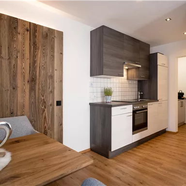 A modern kitchen with wooden details and a bright room. The dining table has a cozy atmosphere and the walls are designed in bright colors.