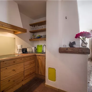Eine moderne Küche mit Holzregalen und eleganten Geräten. Große Fenster lassen viel Licht herein und bieten Aussicht auf die Umgebung.