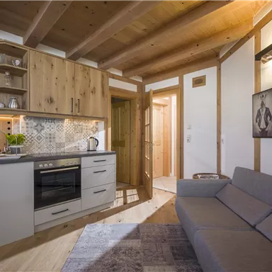Eine moderne Küche mit Holzelementen und einem gemütlichen Wohnbereich. Der Raum ist gut beleuchtet und hat einen warmen, einladenden Charakter.