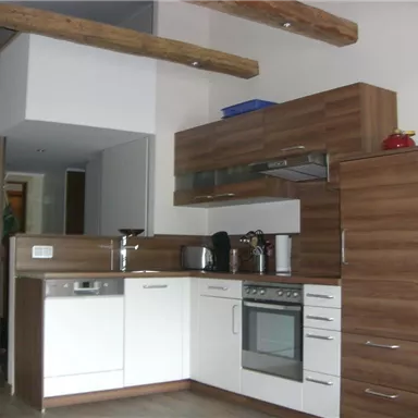 A modern kitchen with wooden and white cabinets. There is an equipped work surface and an oven.