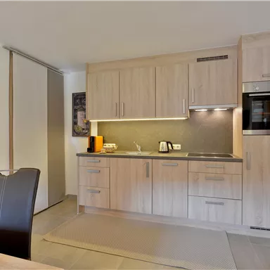 Eine moderne Küche mit hellen Holzschränken und einer eleganten Arbeitsfläche. Sie ist gut ausgestattet mit hochwertigen Elektrogeräten und bietet einen einladenden Raum zum Kochen.