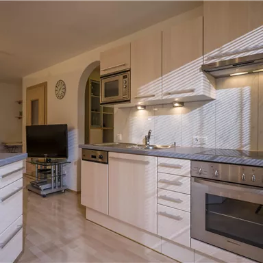A modern kitchen with bright wood furniture and ample space. The appliances are integrated in an elegant design.